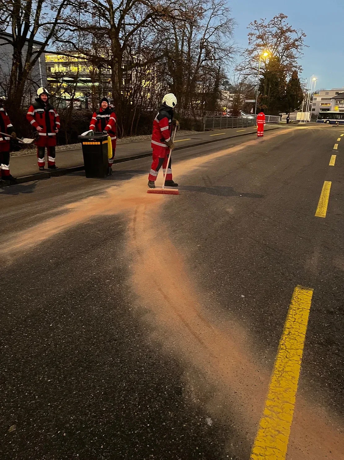 Man sieht Feuerwehrleute, die eine Ölspur beseitigen.